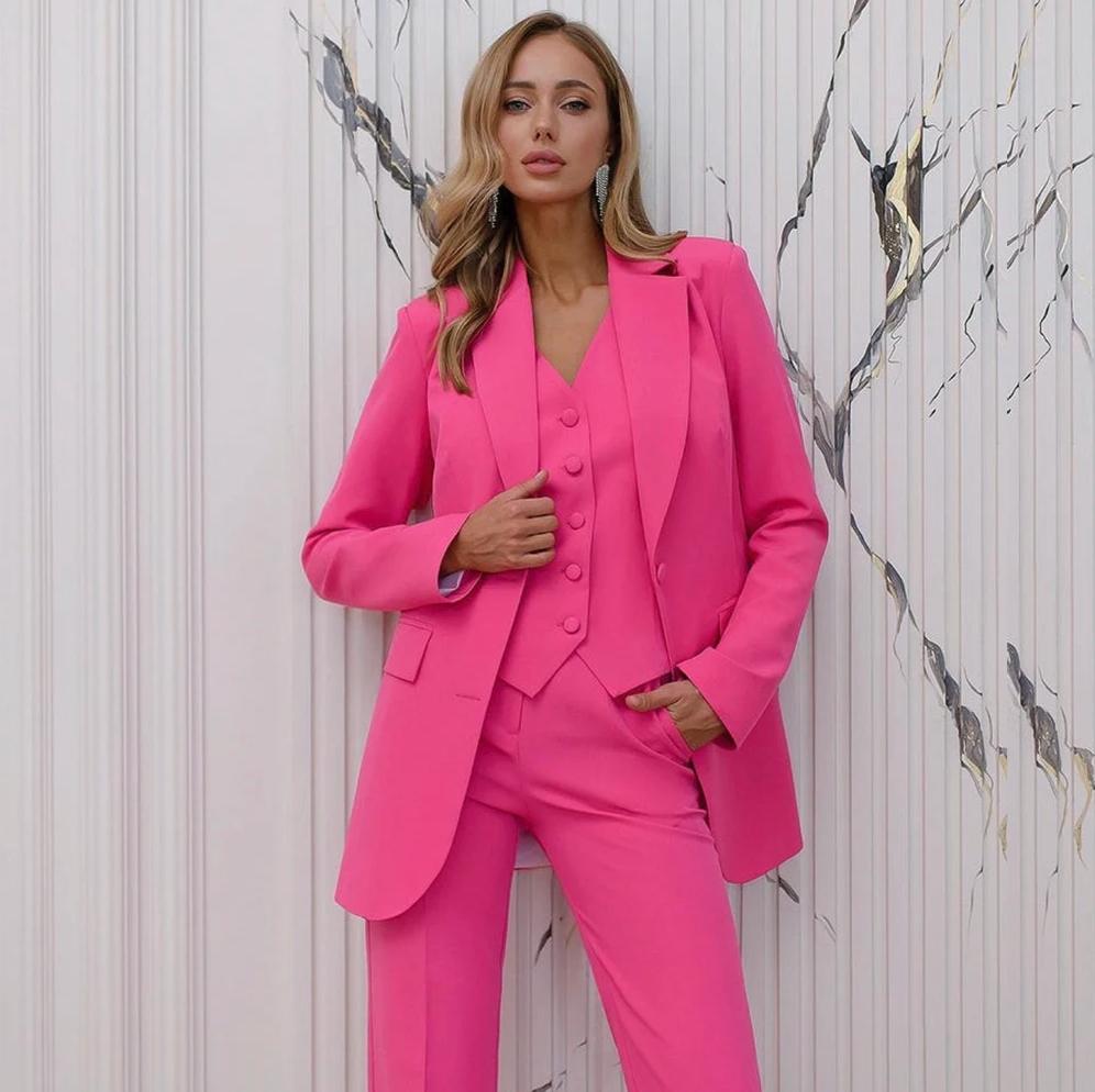 Woman wearing a vibrant pink three-piece serge suit featuring a notched collar jacket, tailored vest, and matching trousers.