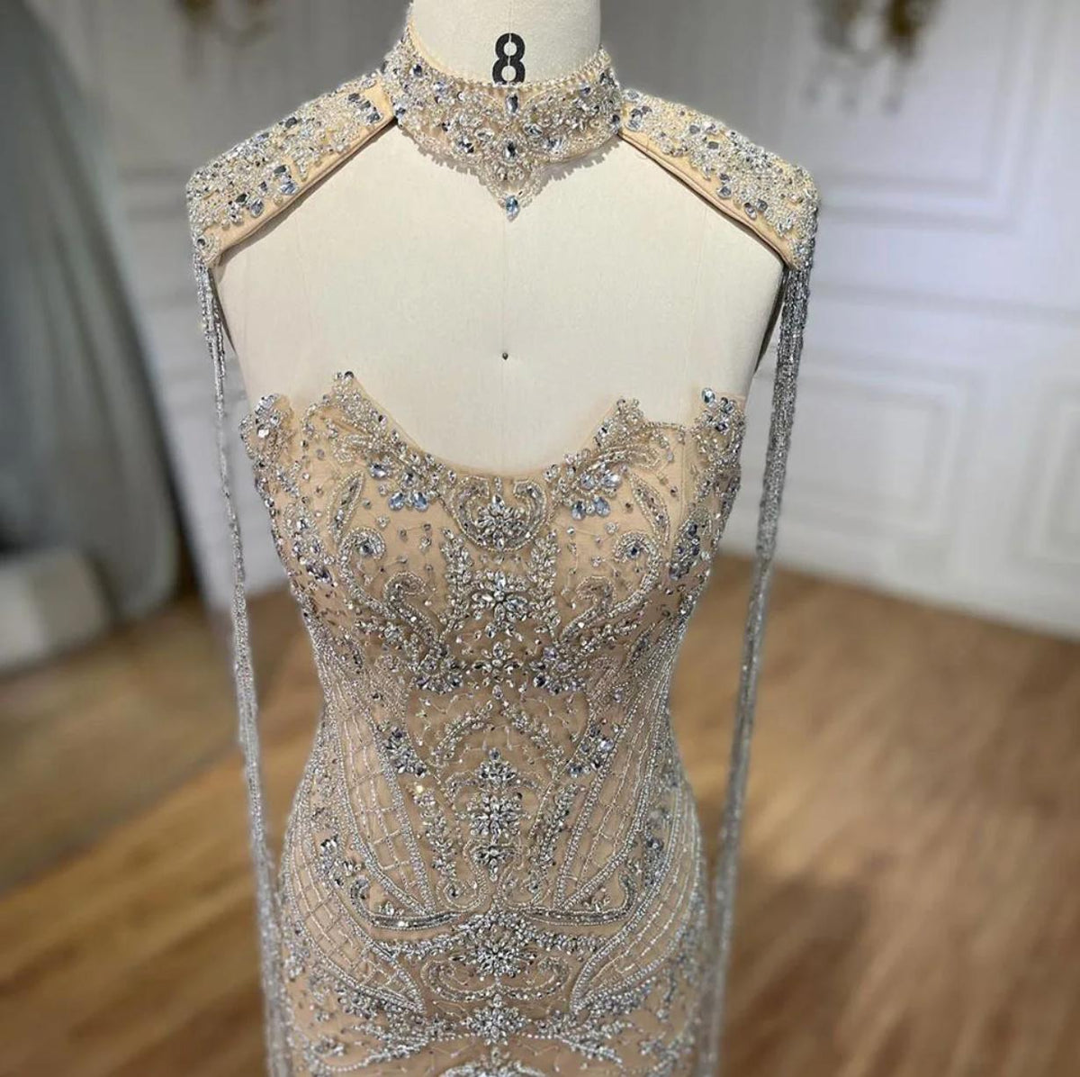 Beaded mermaid wedding gown with crystal embellishments, shimmering sequins, and elegant shoulder tassels on a mannequin.
