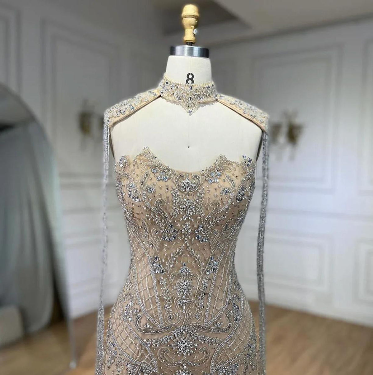 Beaded mermaid wedding gown with shimmering crystals, sequins, and delicate tassels on a mannequin.
