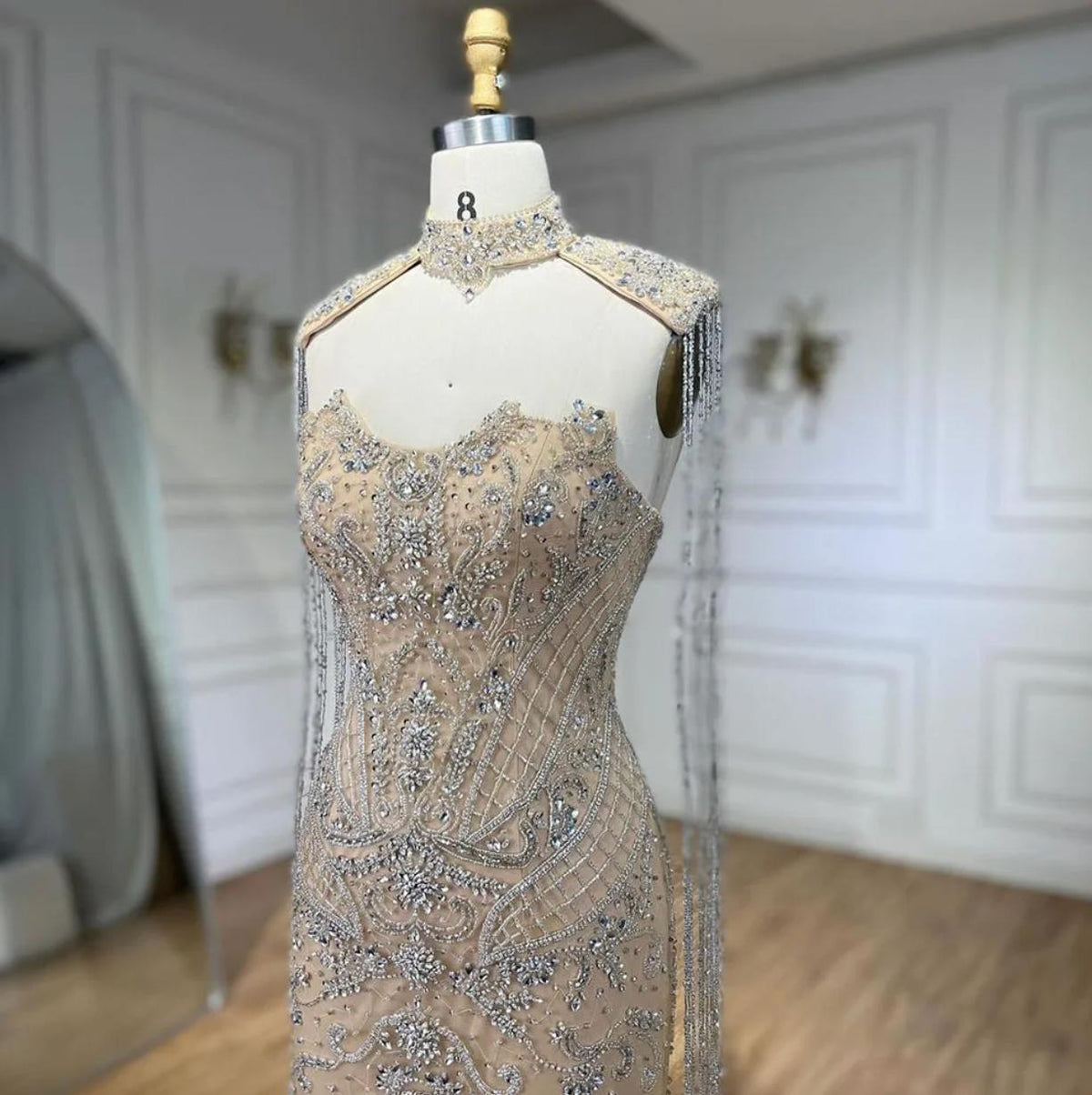 Beaded mermaid wedding gown with shimmering crystals, sequins, and dramatic silver tassels on a mannequin.