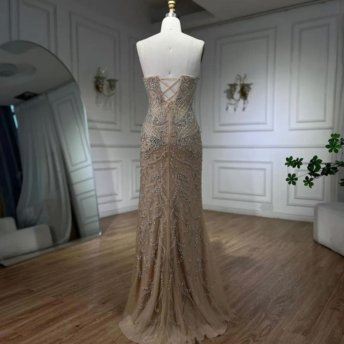 Beige mermaid wedding gown with intricate silver beading, sequins, crystals, and a lace-up back on a dress form.