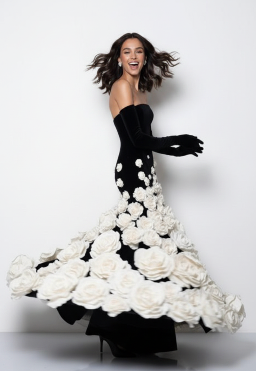 Woman wearing a black velvet strapless evening gown with 3D white floral embellishments and matching opera gloves.