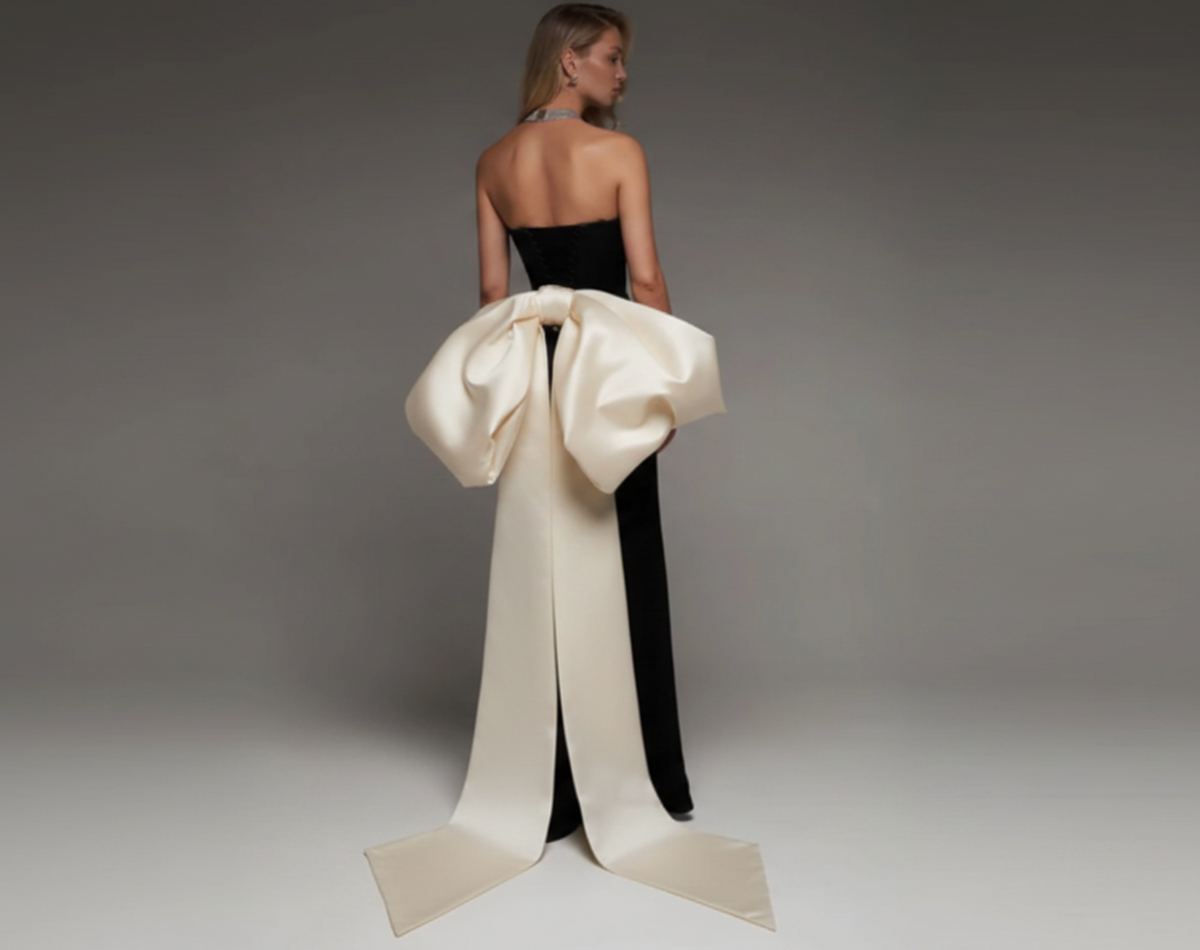 Strapless black mermaid wedding dress with a dramatic oversized white satin bow and long train.