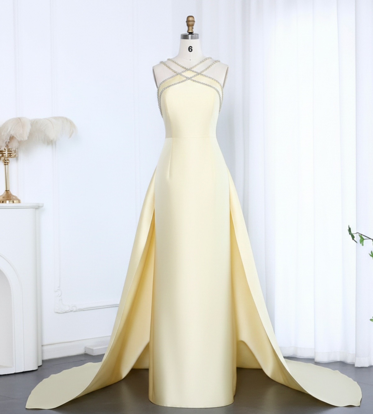 Pale yellow satin mermaid evening gown with a beaded halter neckline and dramatic detachable overskirt train.