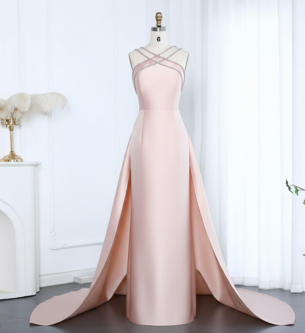 Light pink satin mermaid evening gown with a beaded crisscross halter neckline and a dramatic detachable overskirt.