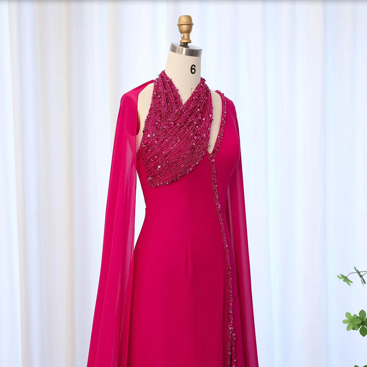 Fuchsia chiffon Selma gown featuring a beaded halter neckline, dramatic cape sleeves, and crystal embellishments.