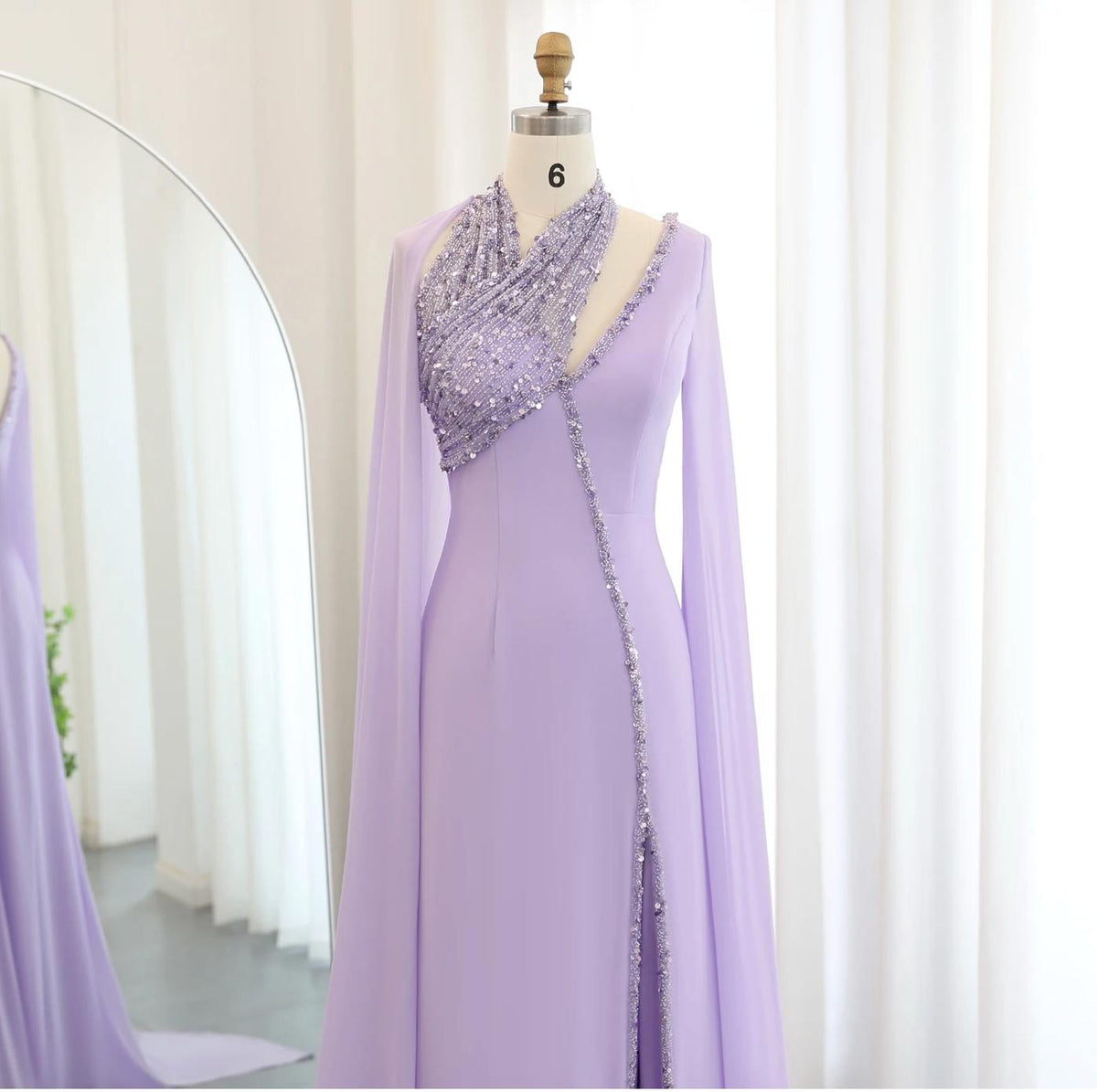Lavender chiffon Selma gown with beaded halter neckline, cape sleeves, and crystal-embellished floor-length silhouette.