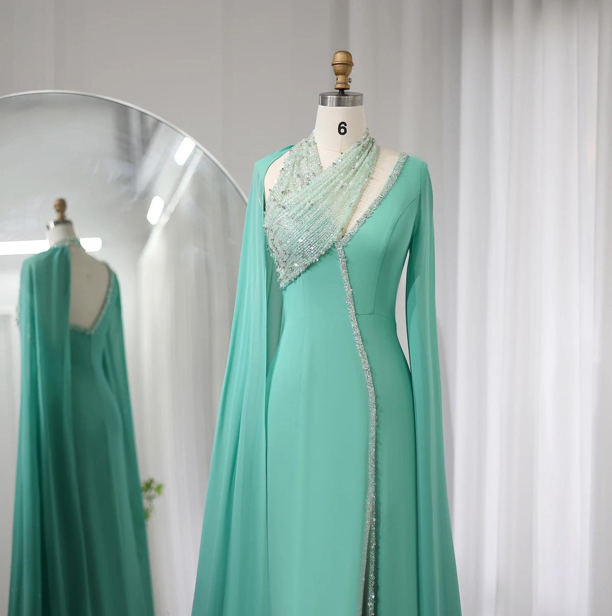 Mint green chiffon floor-length gown with beaded halter neckline, long cape sleeves, and crystal embellishments.