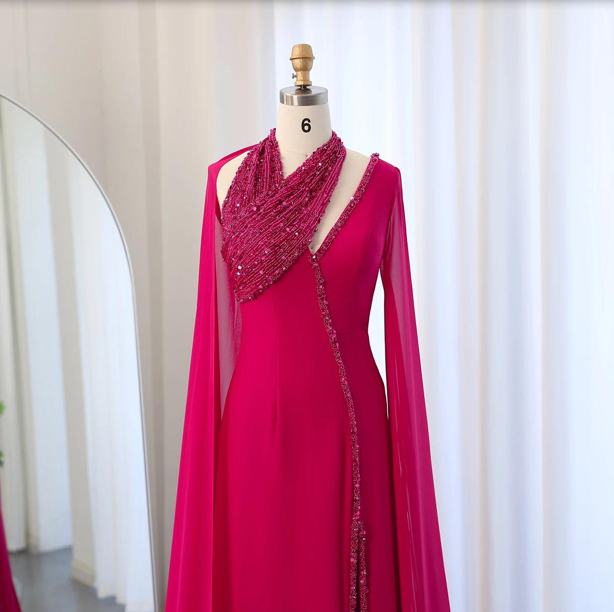 Magenta chiffon Selma gown with beaded halter neckline, cape sleeves, and crystal embellishments on a mannequin.