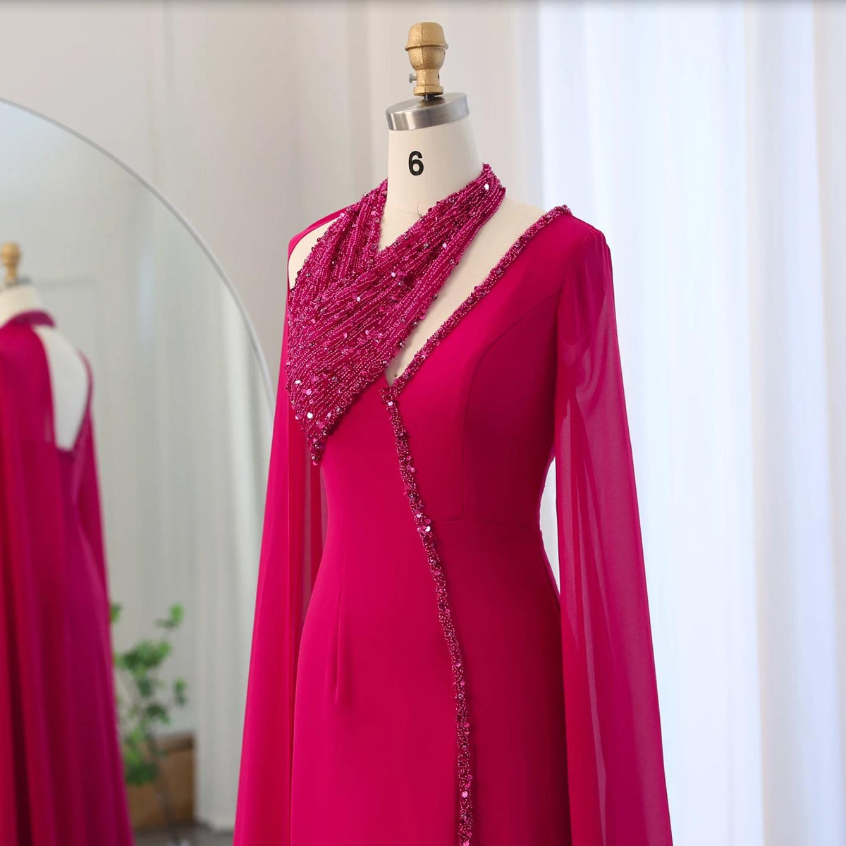 Magenta chiffon Selma gown on a mannequin featuring a beaded halter neckline, cape sleeves, and crystal embellishments.