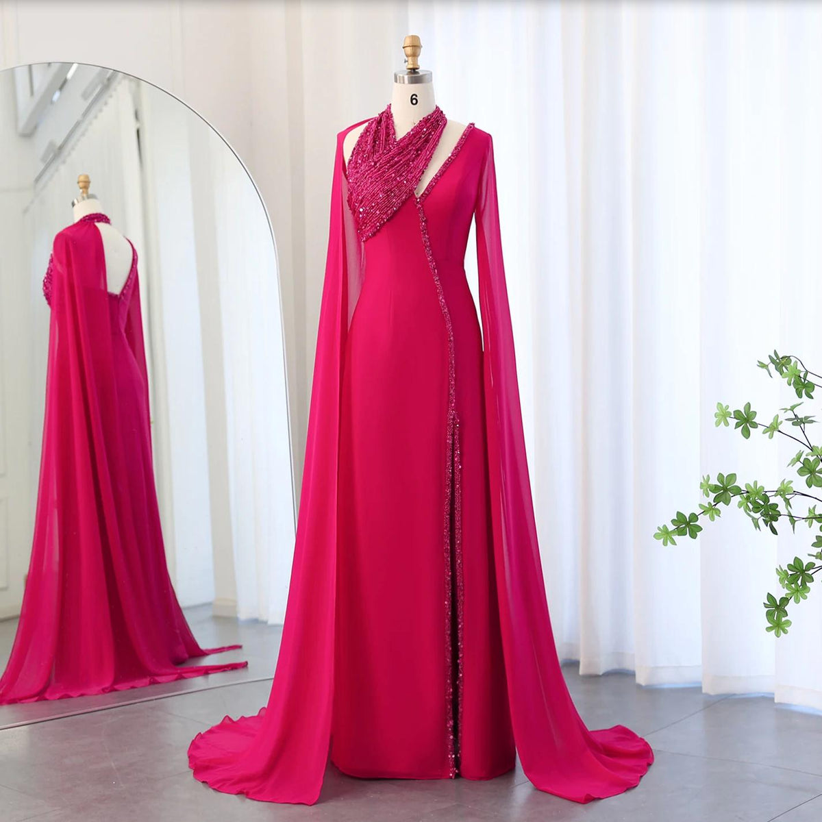 Fuchsia chiffon floor-length gown with beaded halter neckline, dramatic cape sleeves, and a sweeping train on a mannequin.