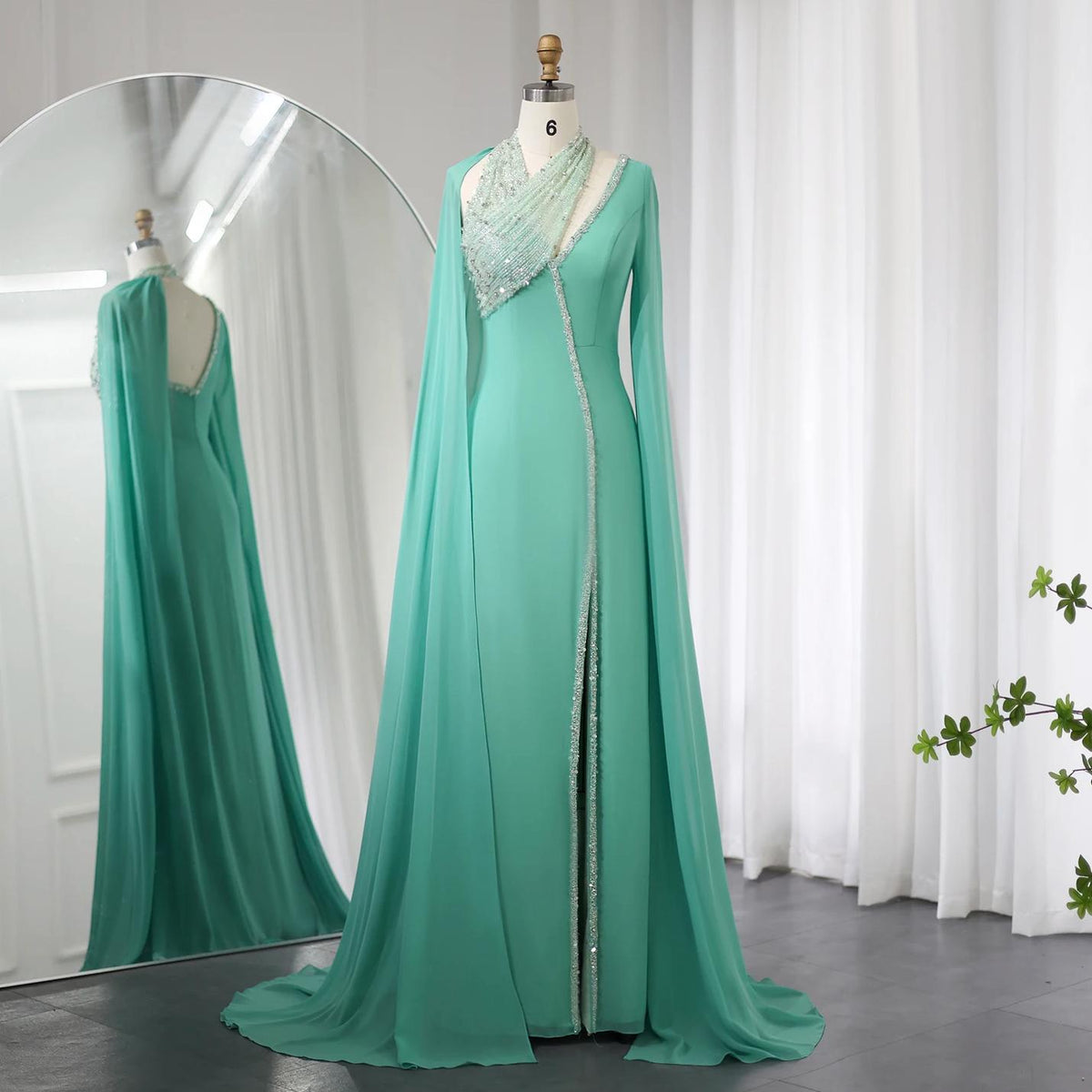 Mint green chiffon floor-length gown with beaded halter neckline, cape sleeves, and crystal-embellished trim on a mannequin.