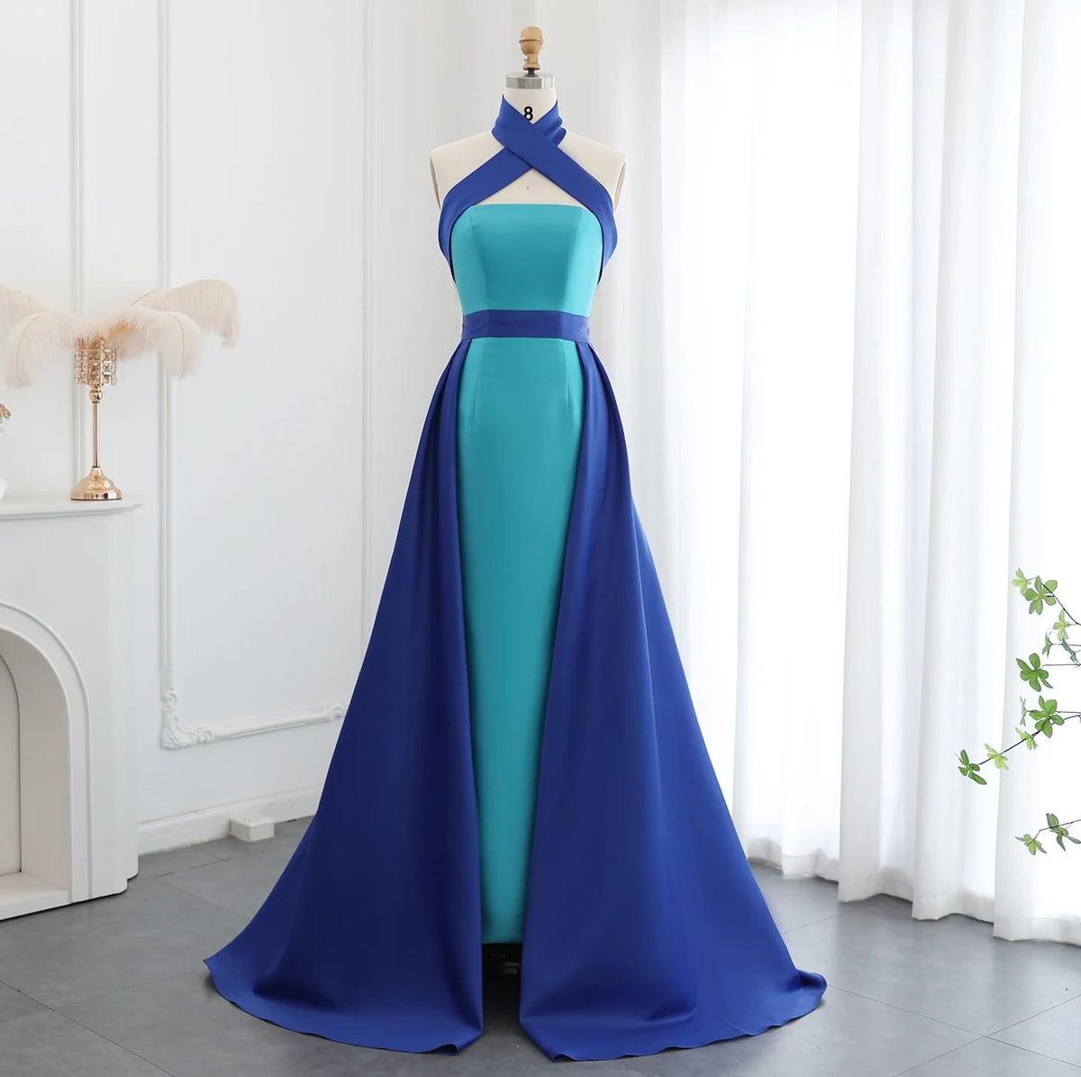 Serene floor-length satin A-line gown with a turquoise bodice, royal blue halter neckline, and matching overskirt.
