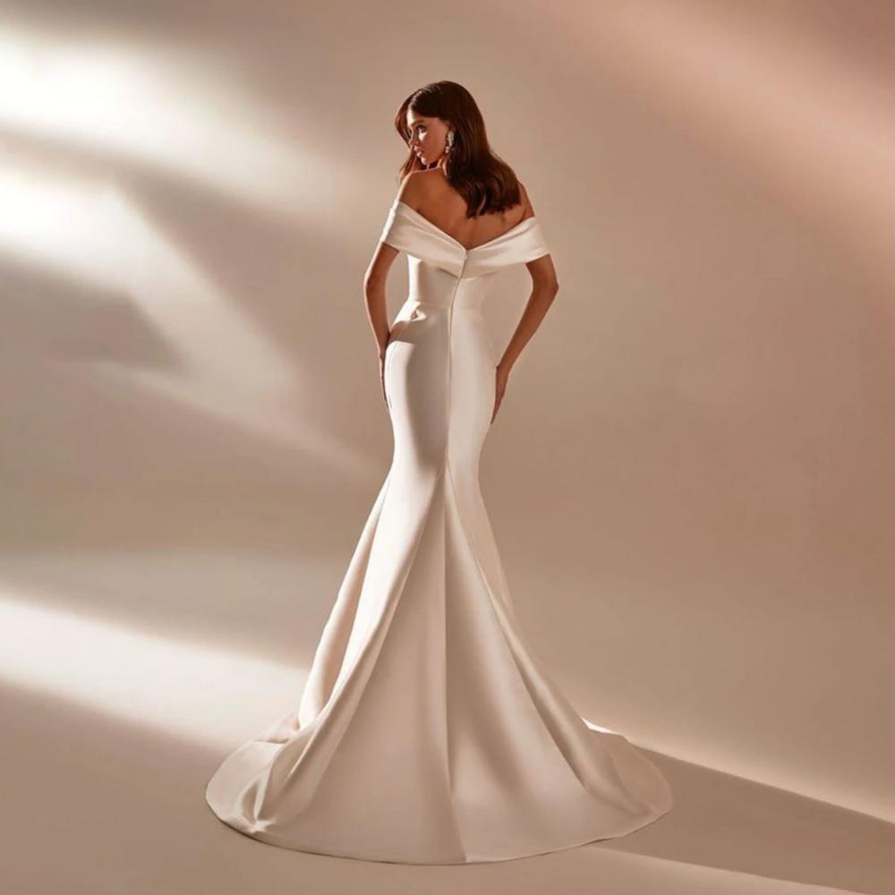 Backless white satin mermaid wedding gown with off-the-shoulder neckline and elegant court train.