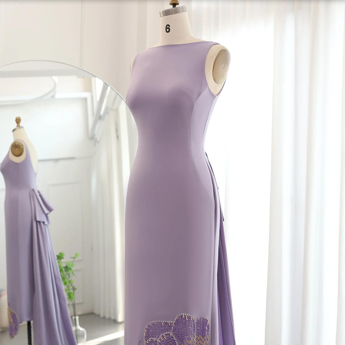 Sleeveless lavender jersey evening gown with beaded butterfly-inspired detailing and a flowing train on a dress form.