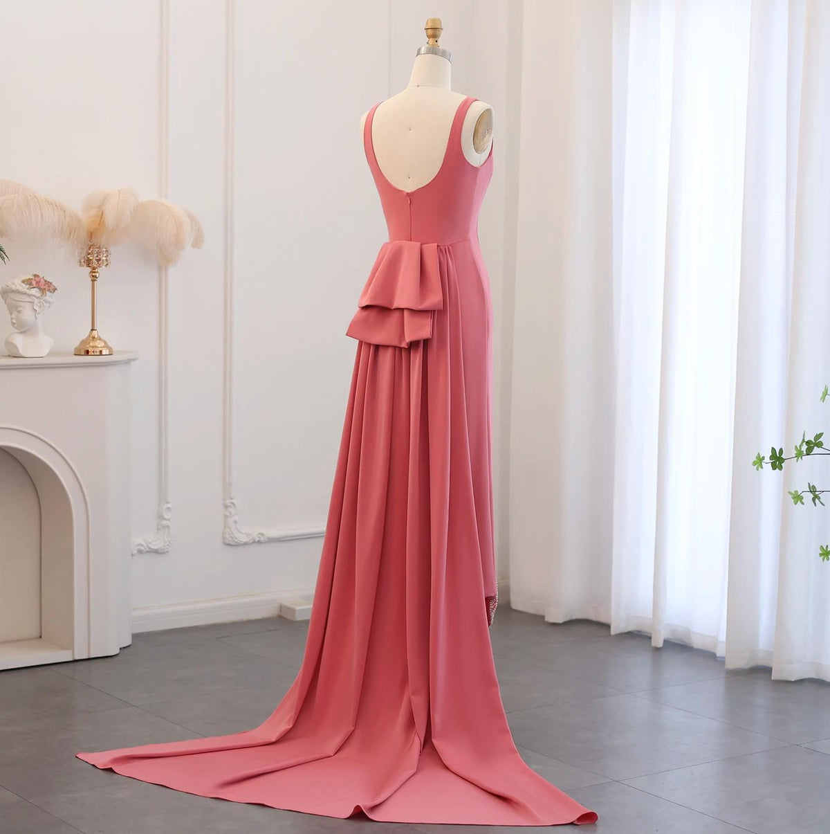 Sleeveless pink jersey evening gown with a back bow detail and floor-length train on a mannequin.