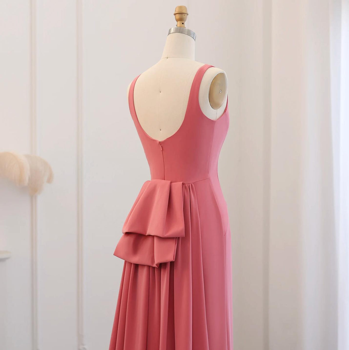 Sleeveless pink jersey evening gown with a scoop back and layered butterfly-inspired bow detail on a mannequin.
