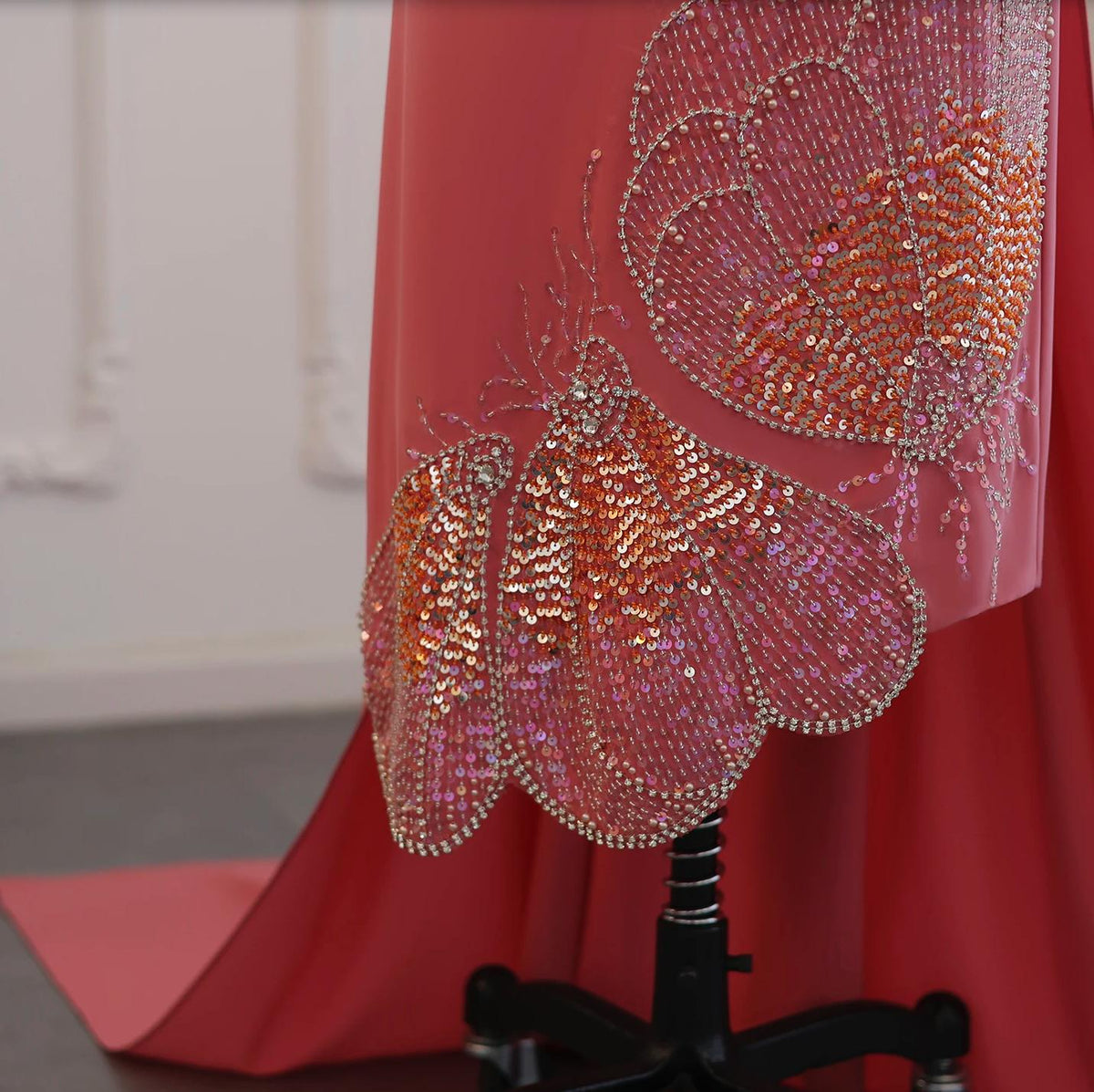 Coral jersey evening gown featuring intricate butterfly-inspired beadwork, shimmering sequins, and crystal embellishments.
