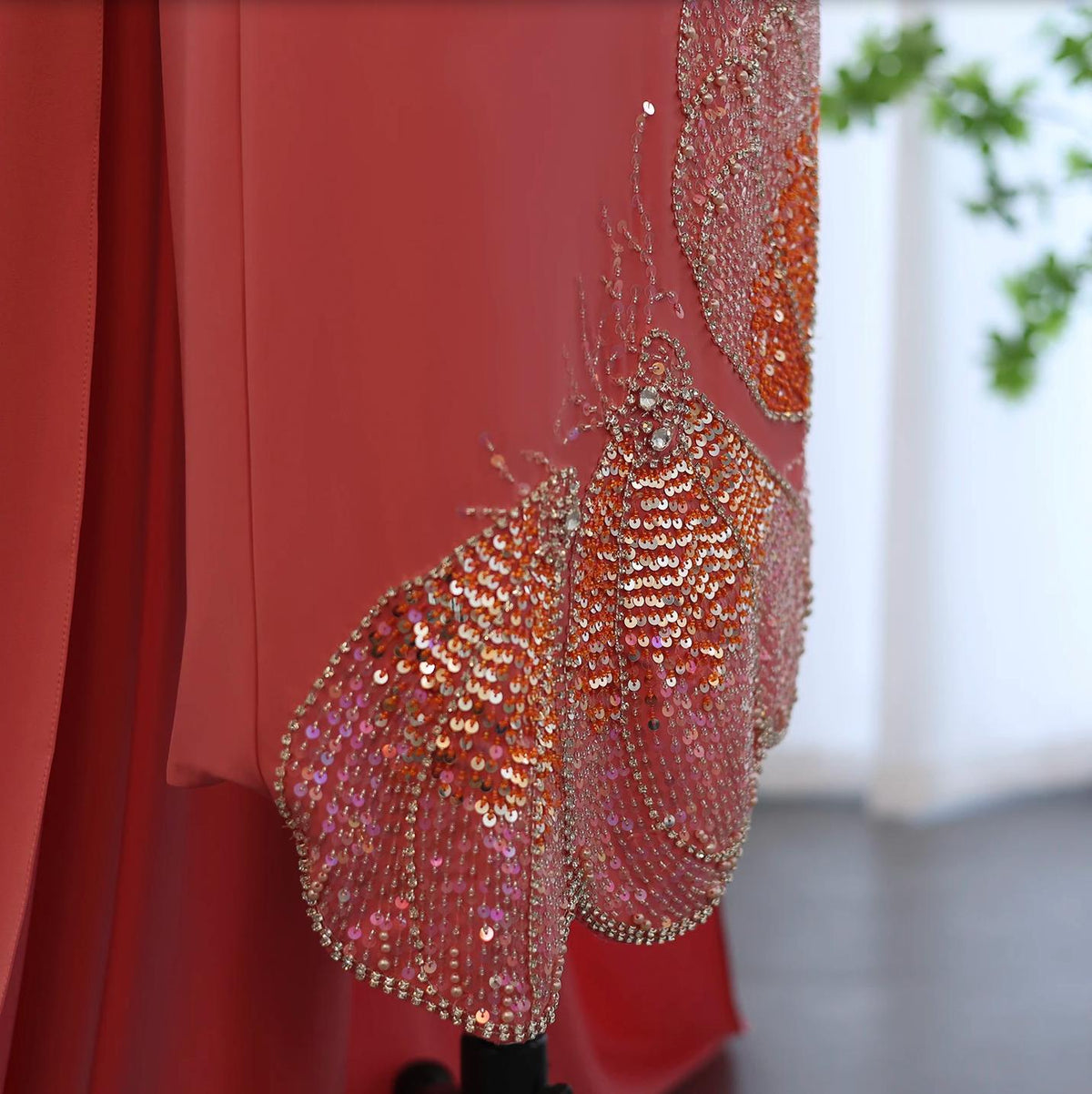 Coral jersey evening gown featuring intricate butterfly-inspired beading, sparkling sequins, and crystal embellishments.