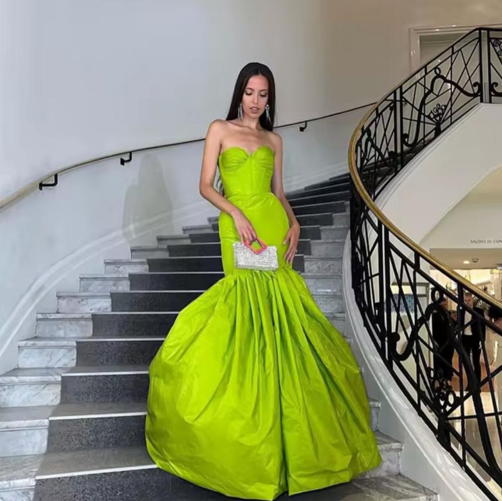 Lime green strapless taffeta mermaid gown with pleated bodice and dramatic flared skirt on a staircase.