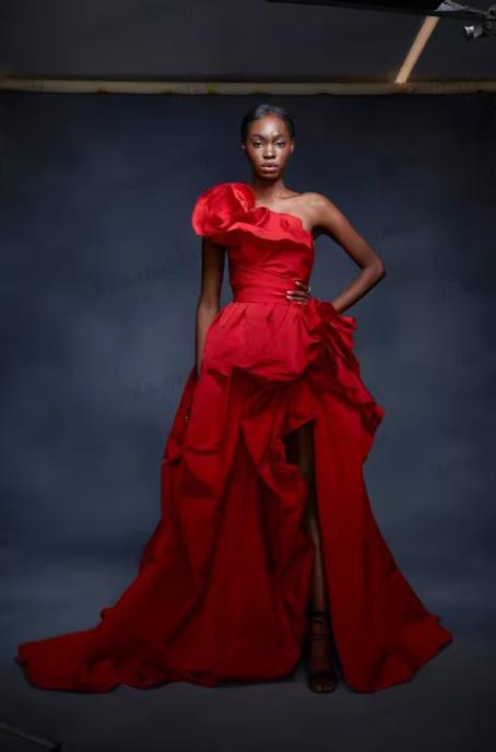 Model wearing a red one-shoulder satin gown with 3D floral detail, a high-low skirt, and a dramatic chapel train.