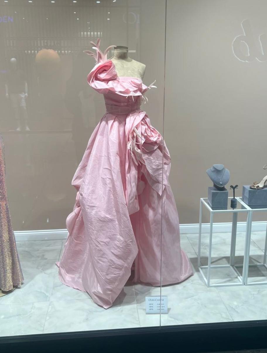 Pink one-shoulder satin A-line gown featuring dramatic 3D floral accents and a flowing floor-length skirt on display.