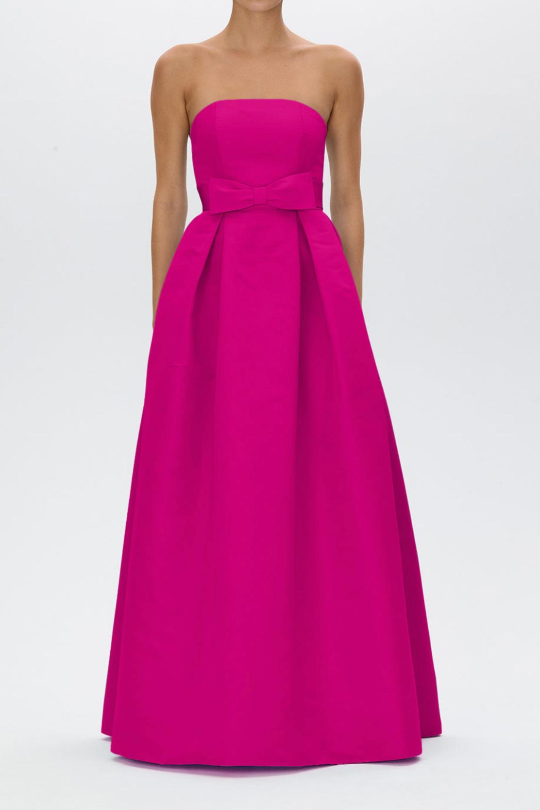 Strapless fuchsia satin gown with a pleated full-length skirt and a removable bow belt at the natural waist.