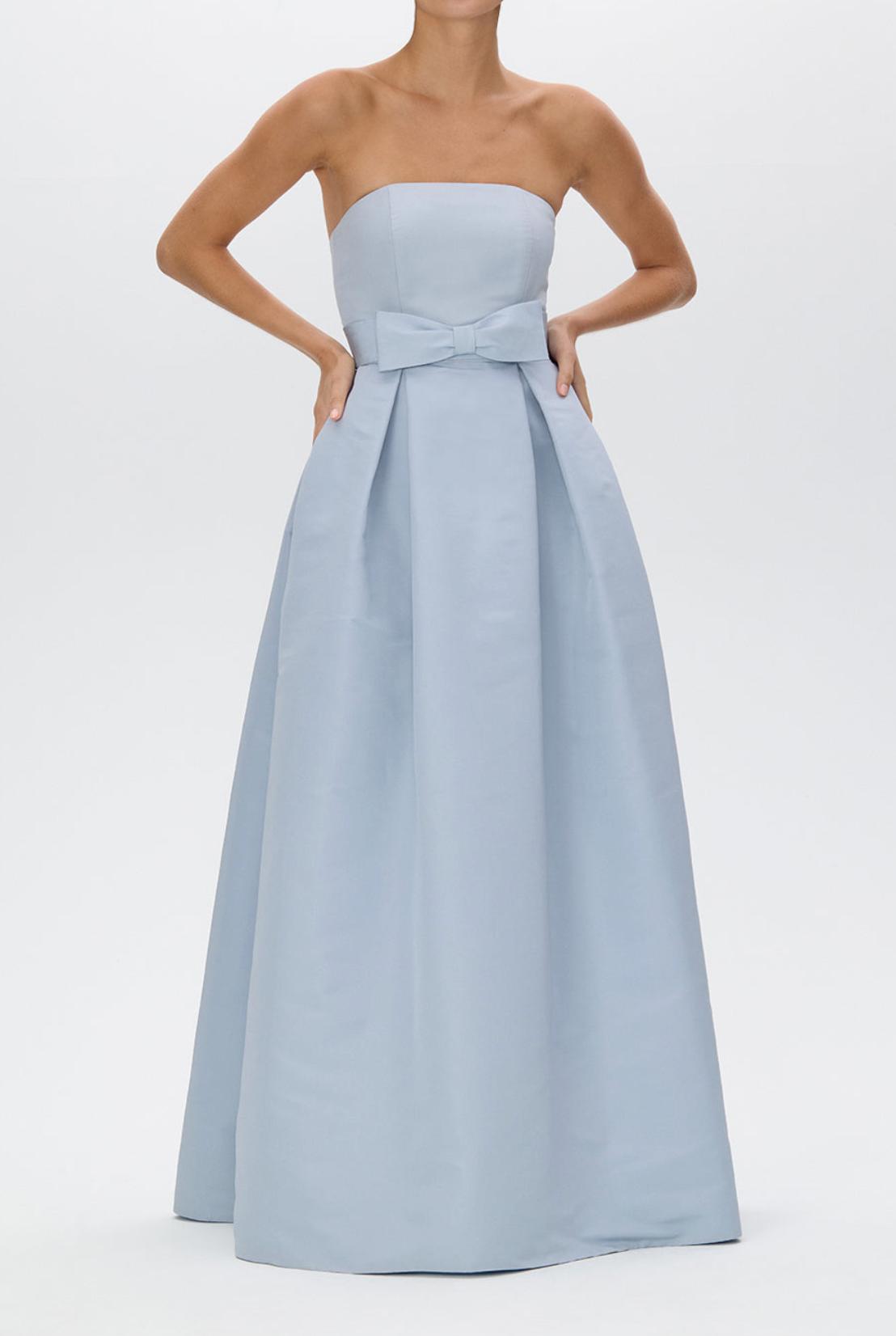 Strapless light blue satin evening gown with a pleated full-length skirt and a removable bow belt at the waist.