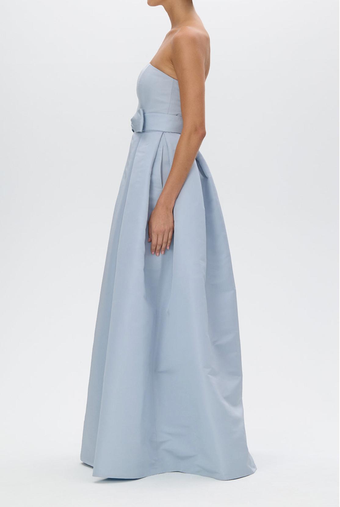 Strapless light blue satin evening gown with a pleated full-length skirt and a removable bow belt at the waist.