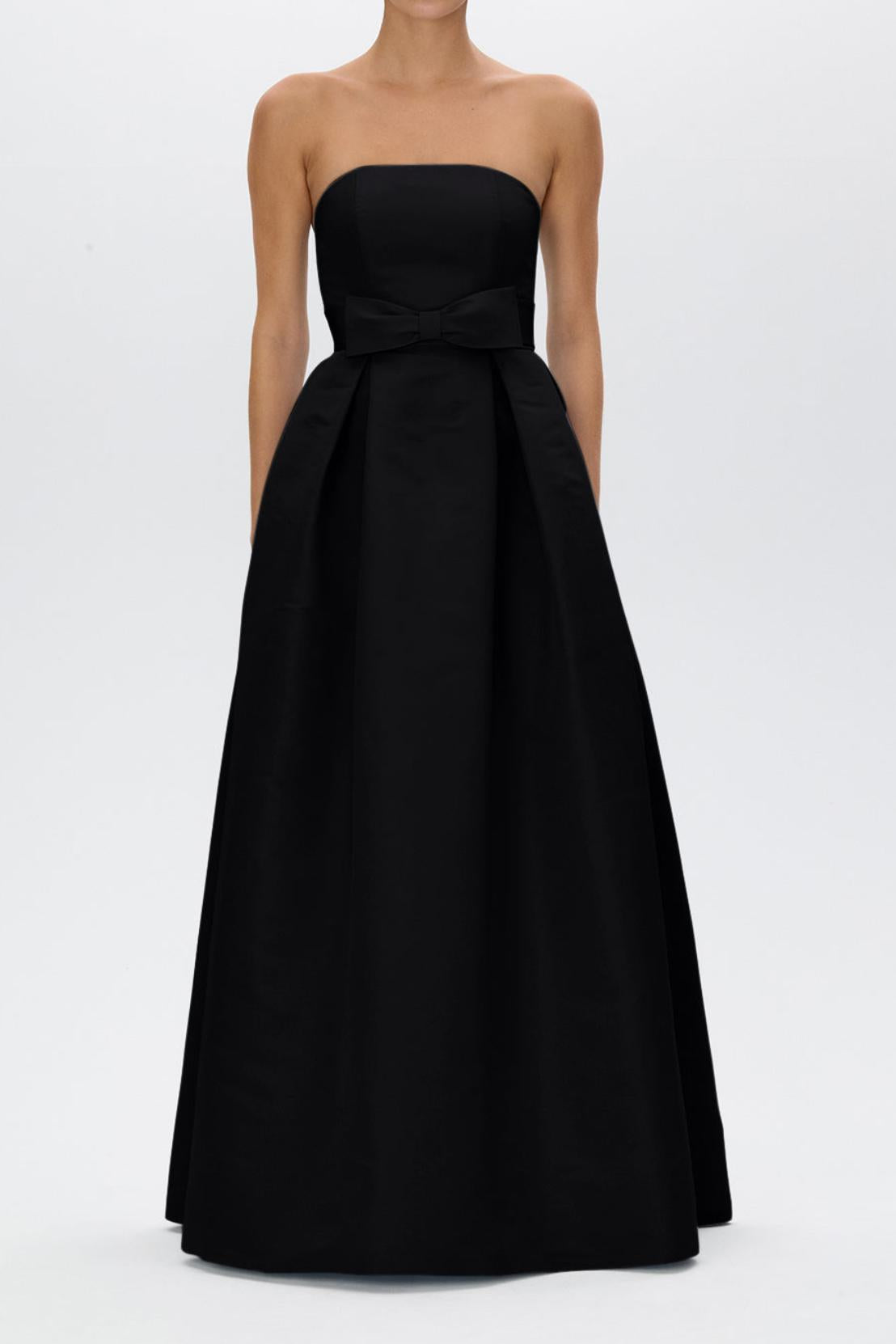 Strapless black satin evening gown with a pleated full-length skirt and a removable bow belt at the natural waist.