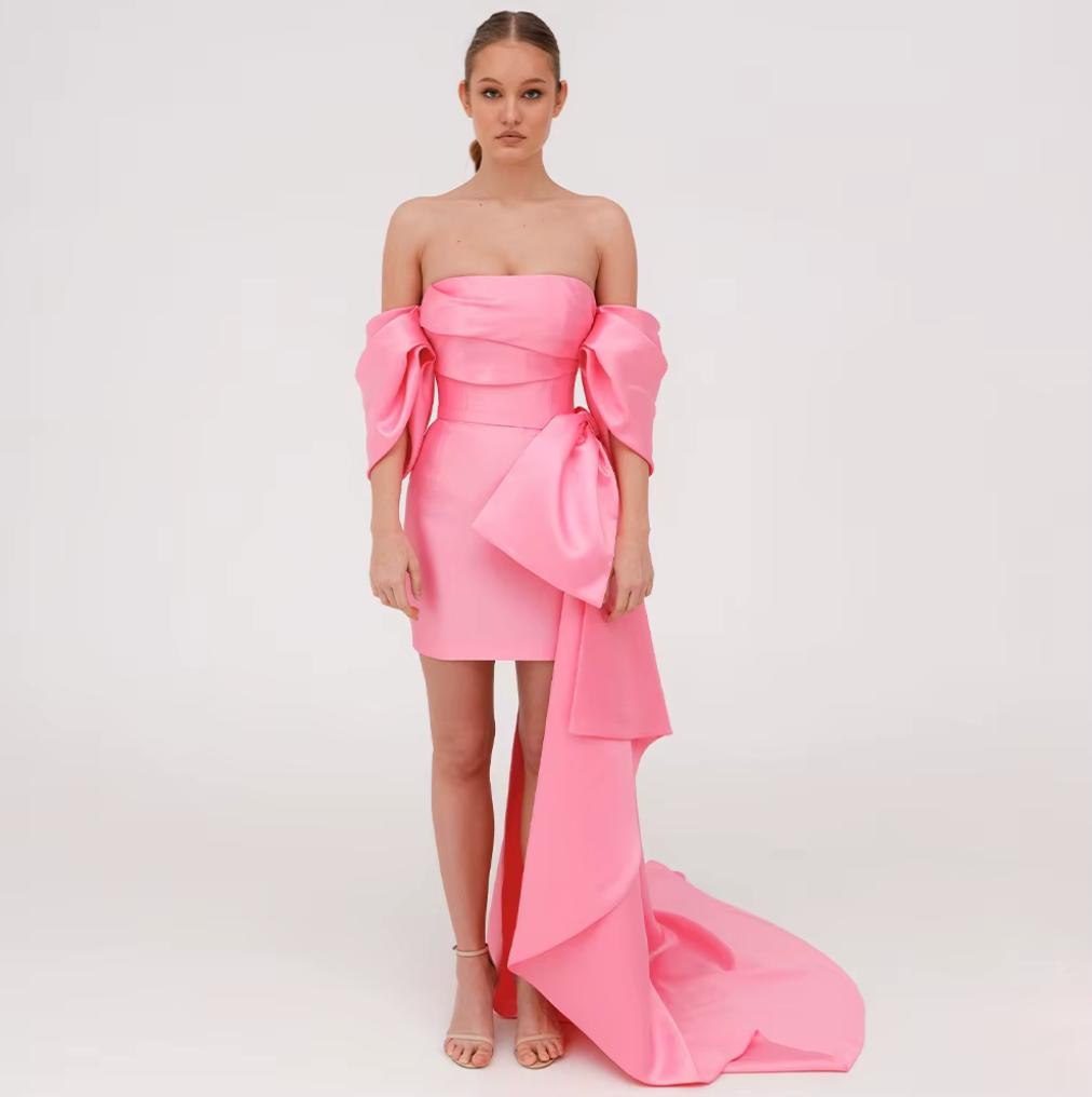 Pink strapless Mikado mini dress with structured corset bodice, off-shoulder sleeves, and a dramatic side bow train.
