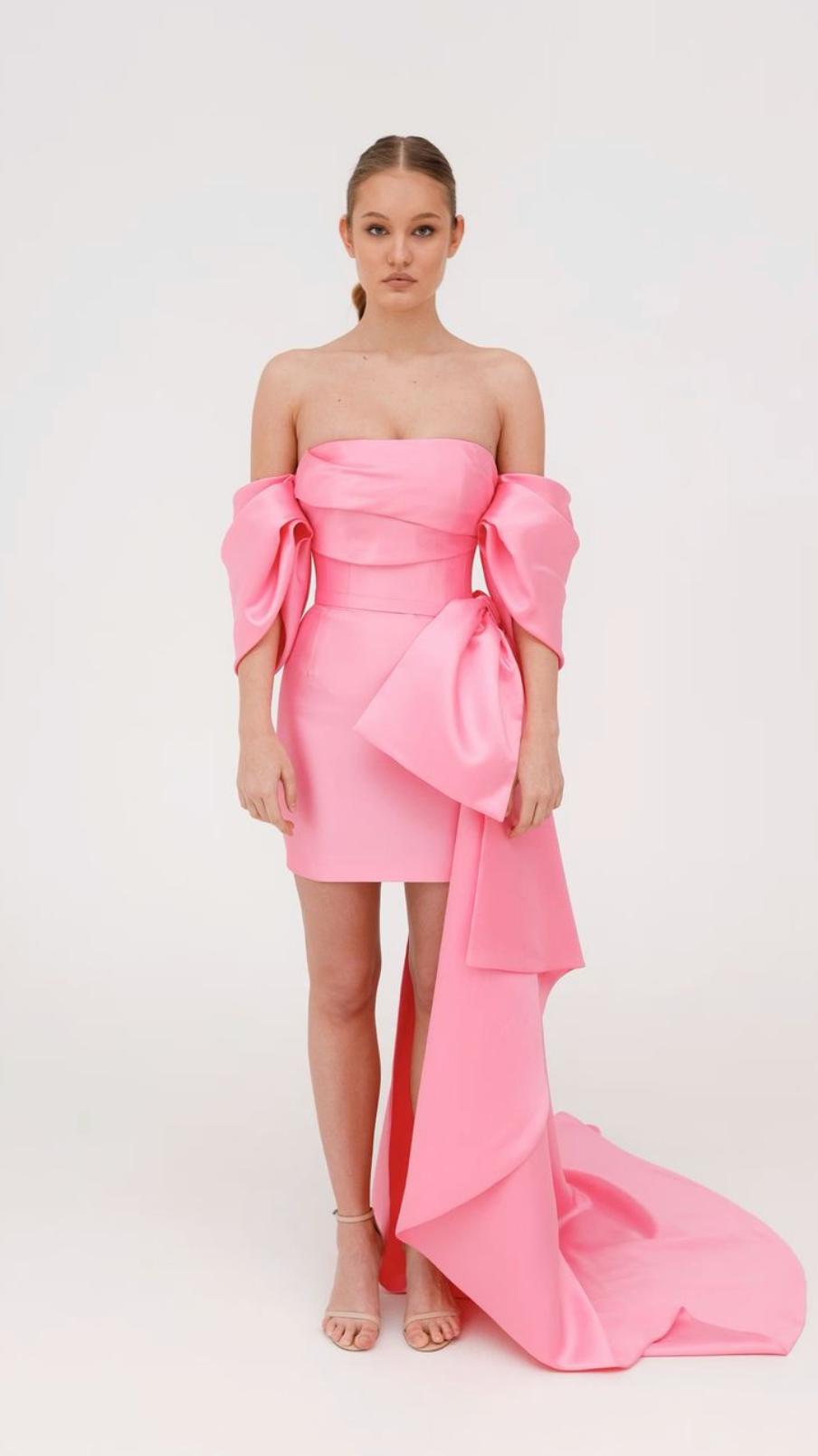 Pink strapless Mikado mini dress with structured corset bodice, off-shoulder sleeves, and a dramatic side bow train.
