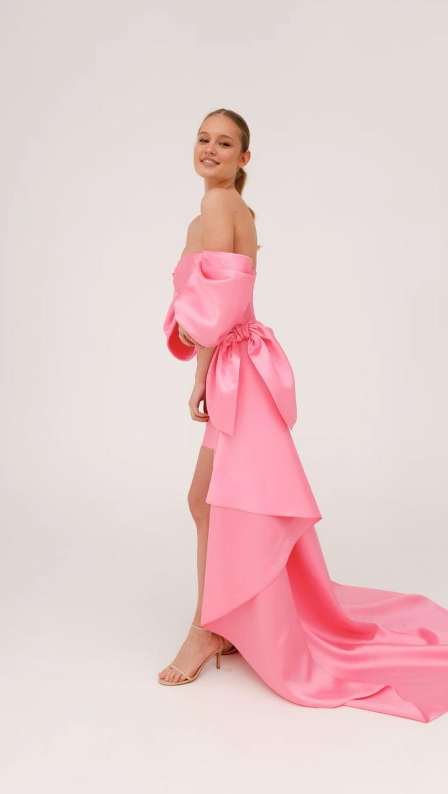 Strapless pink Mikado mini dress with structured corset back, dramatic side bow, and flowing train.