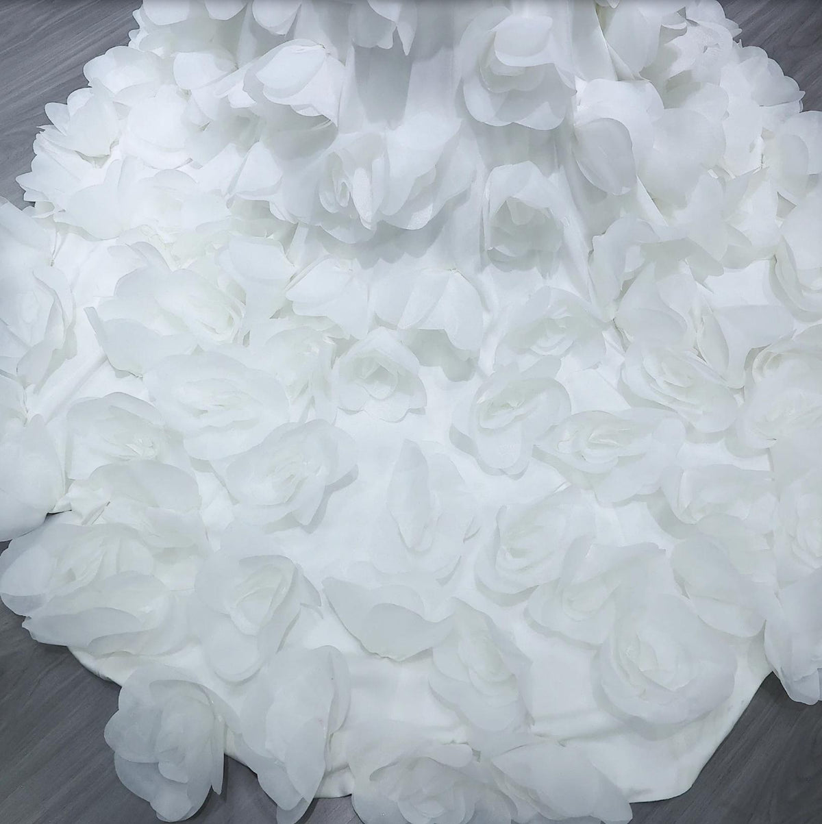 White satin evening gown featuring delicate 3D floral fabric petals in a floor-length mermaid silhouette.