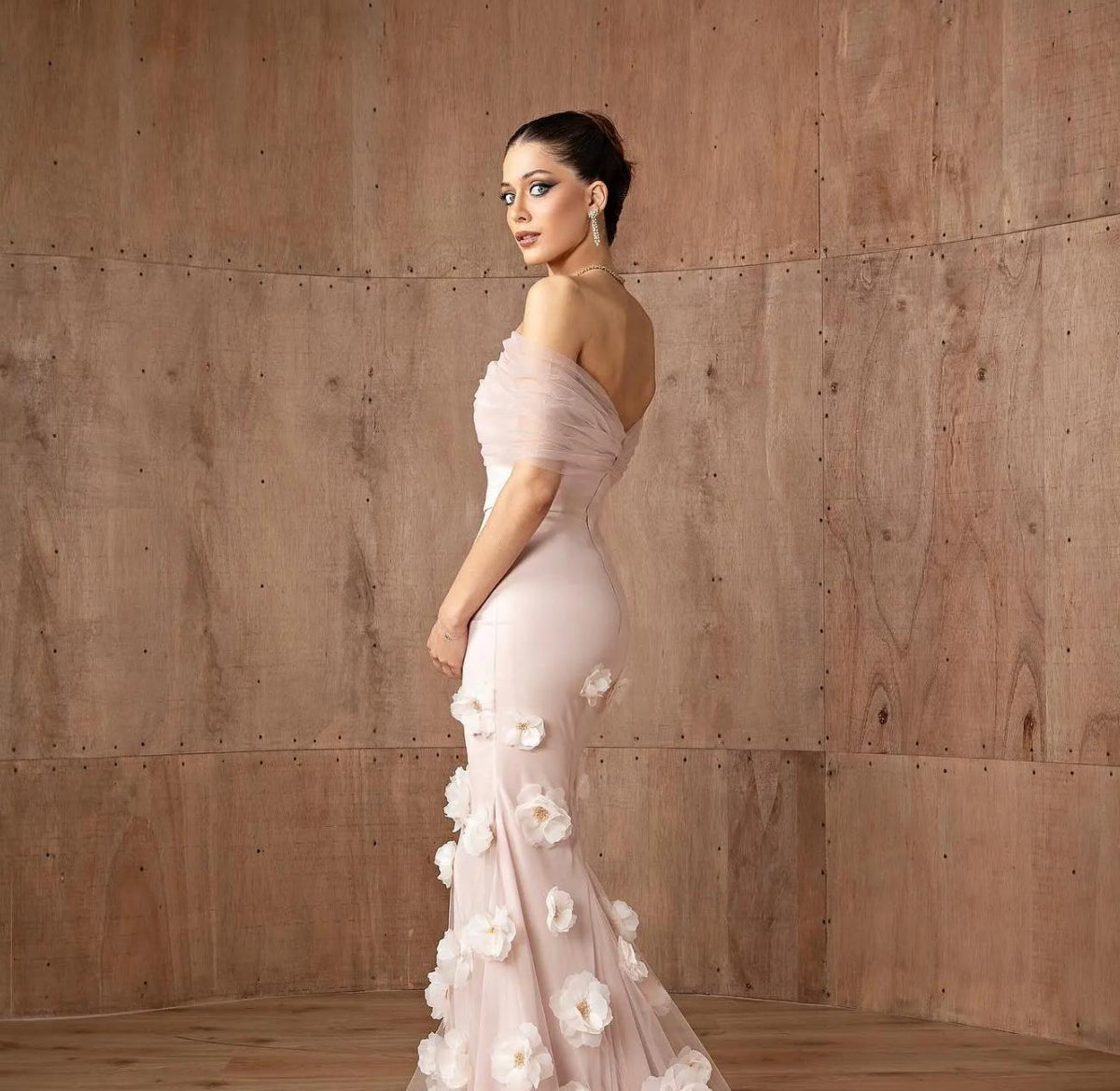 Daring pink off-shoulder mermaid gown in satin with delicate 3D floral accents and a floor-length silhouette.
