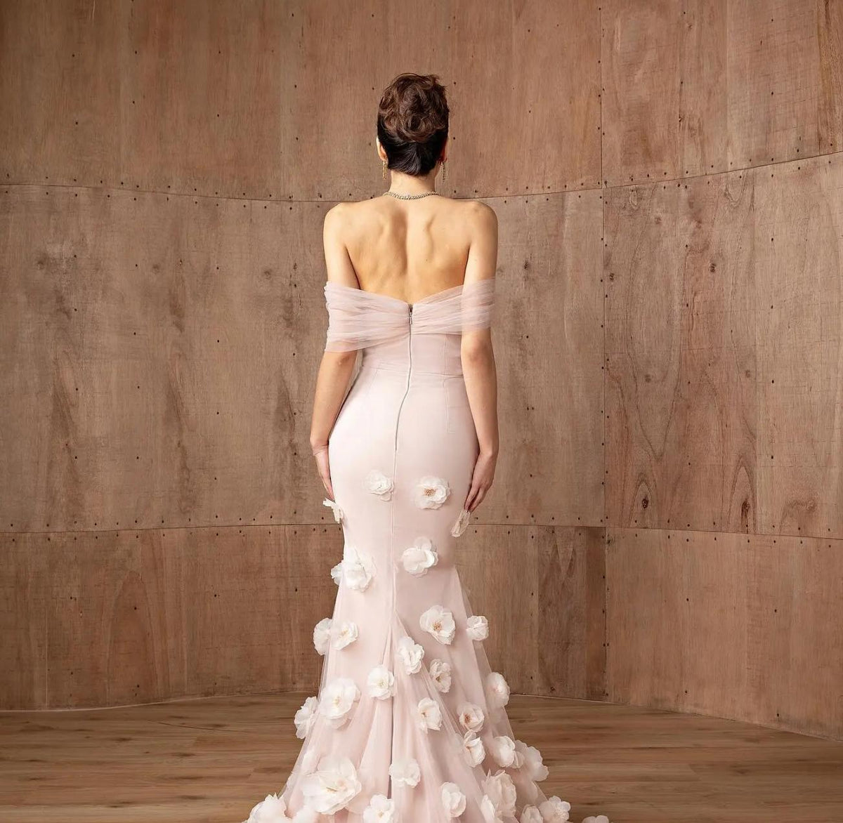 Daring pink off-shoulder mermaid gown in satin with delicate 3D floral accents and a floor-length silhouette.