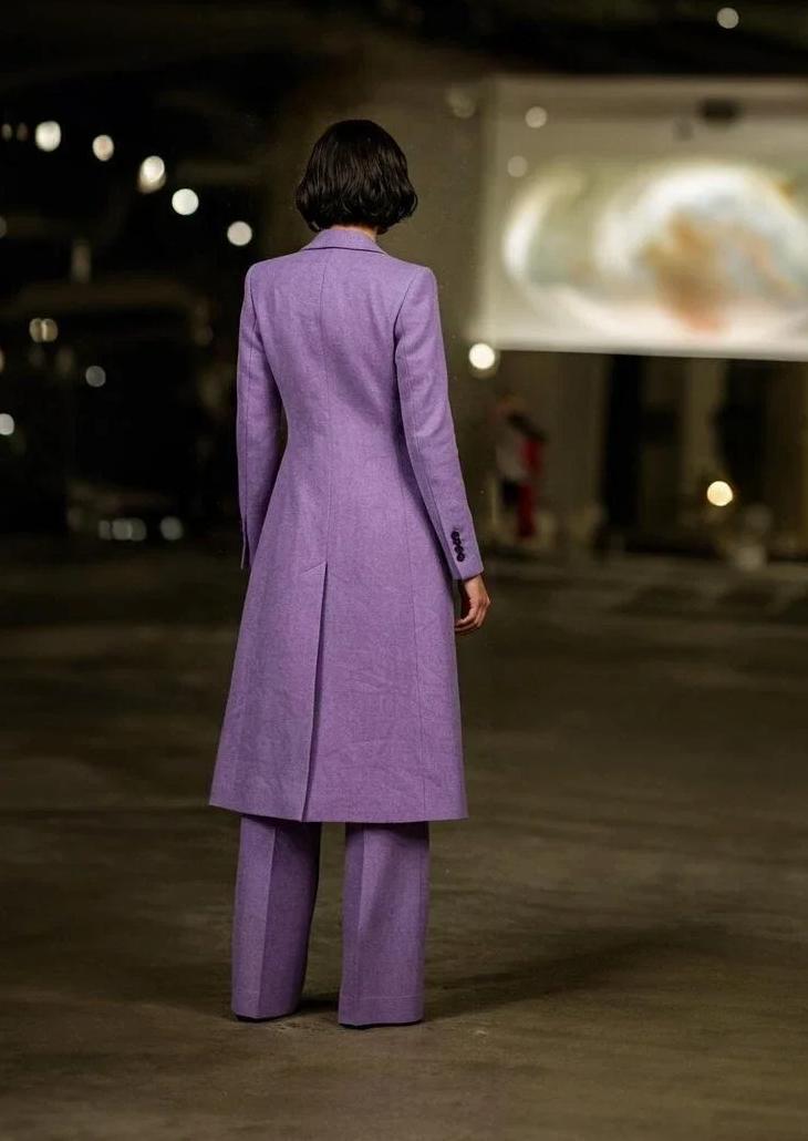 Woman wearing a purple linen three-piece suit with a mid-length blazer and wide-leg trousers, viewed from behind.