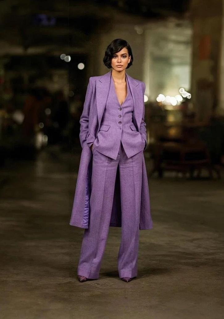Woman wearing a purple linen three-piece suit with a long blazer, buttoned vest, and wide-leg trousers.