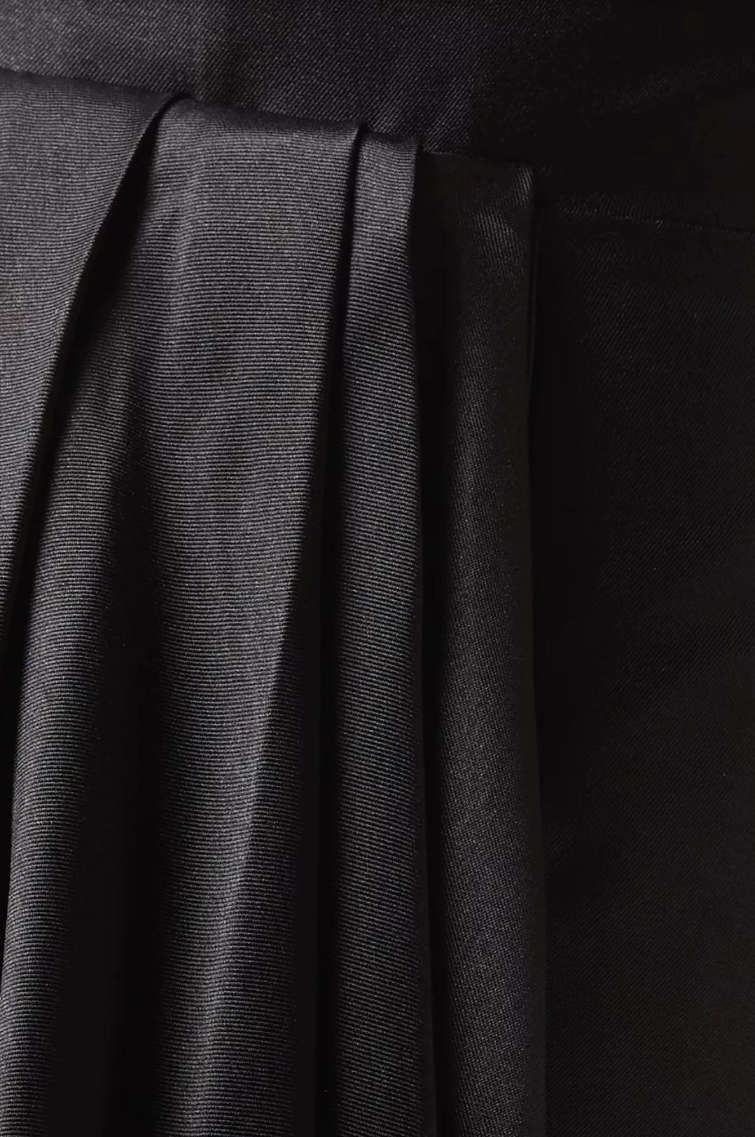 Close-up of black twill fabric featuring elegant, structured pleats from the Talisman strapless gown.