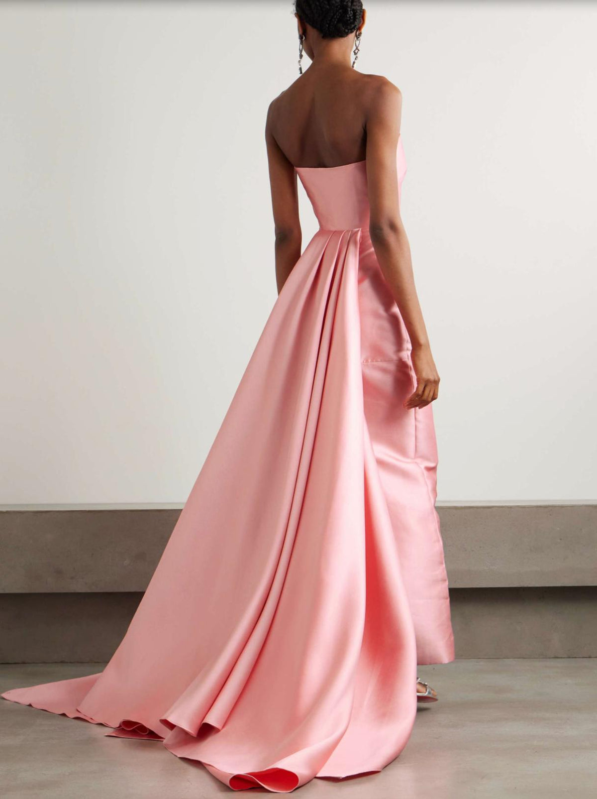 Back view of a pink strapless satin gown featuring a dramatic floor-sweeping detachable train and elegant twill fabric.