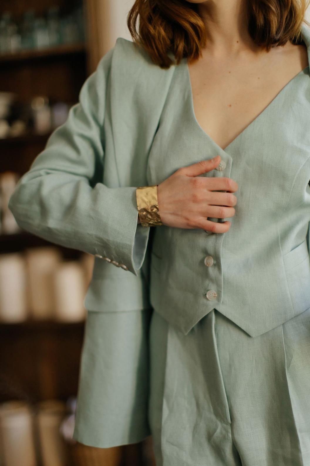 Light green linen three-piece suit featuring a tailored jacket, button-down vest, and matching palazzo pants.