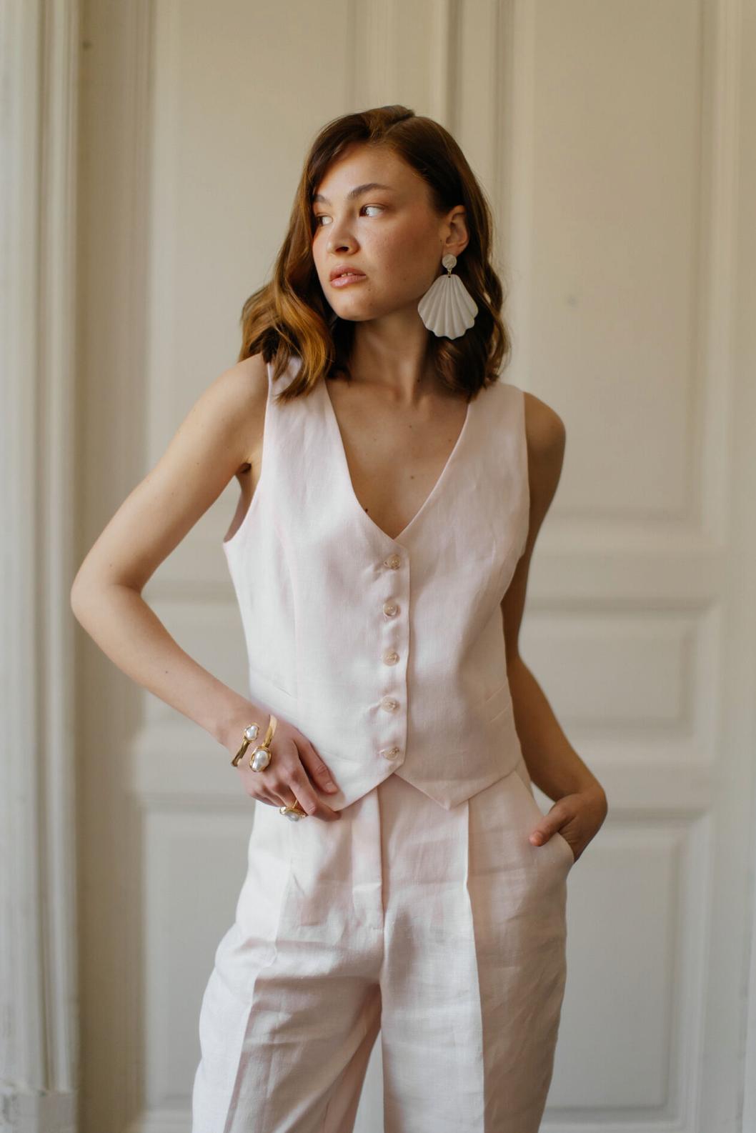 Woman wearing a pale pink linen vest and matching tailored trousers from the Taos three-piece set.