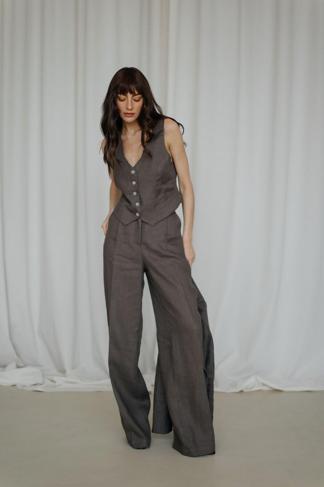 Woman wearing a dark brown linen three-piece suit with a button-up vest and flowing palazzo pants.