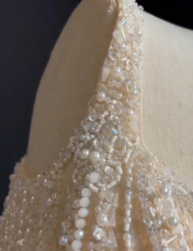 Close-up of a champagne tulle dress featuring intricate hand-sewn beads, shimmering sequins, and crystals on the bodice.