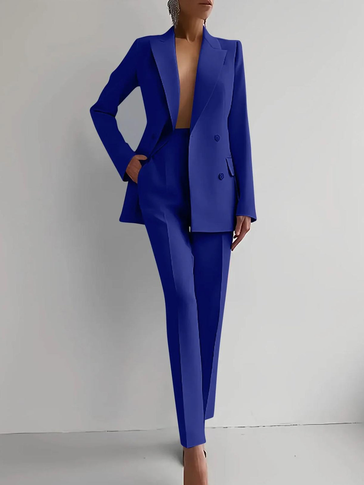 Woman wearing a bold blue double-breasted Italian satin two-piece suit with tailored ankle-length trousers.