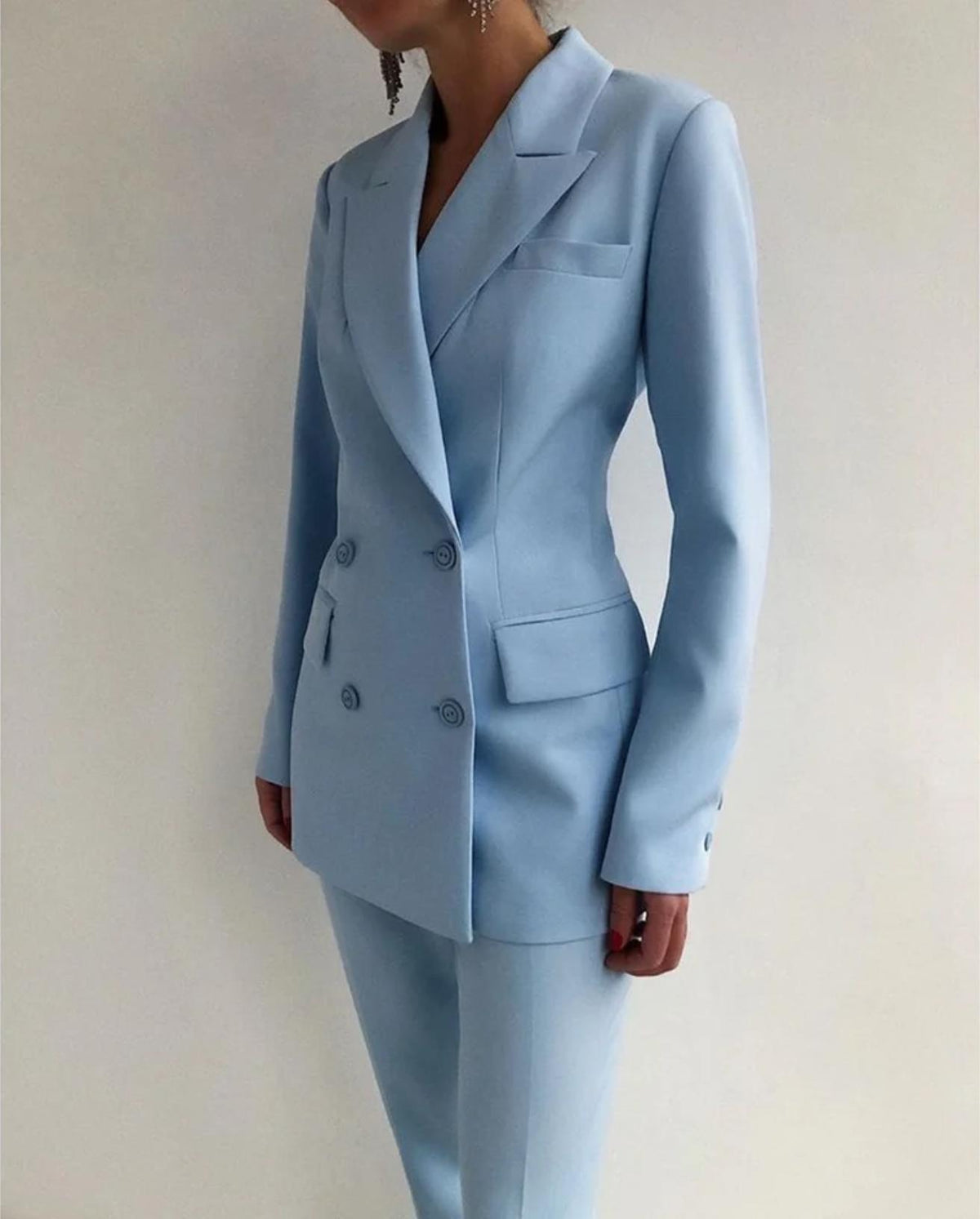 Woman wearing a light blue Italian satin double-breasted suit with a tailored silhouette and sharp lapels.
