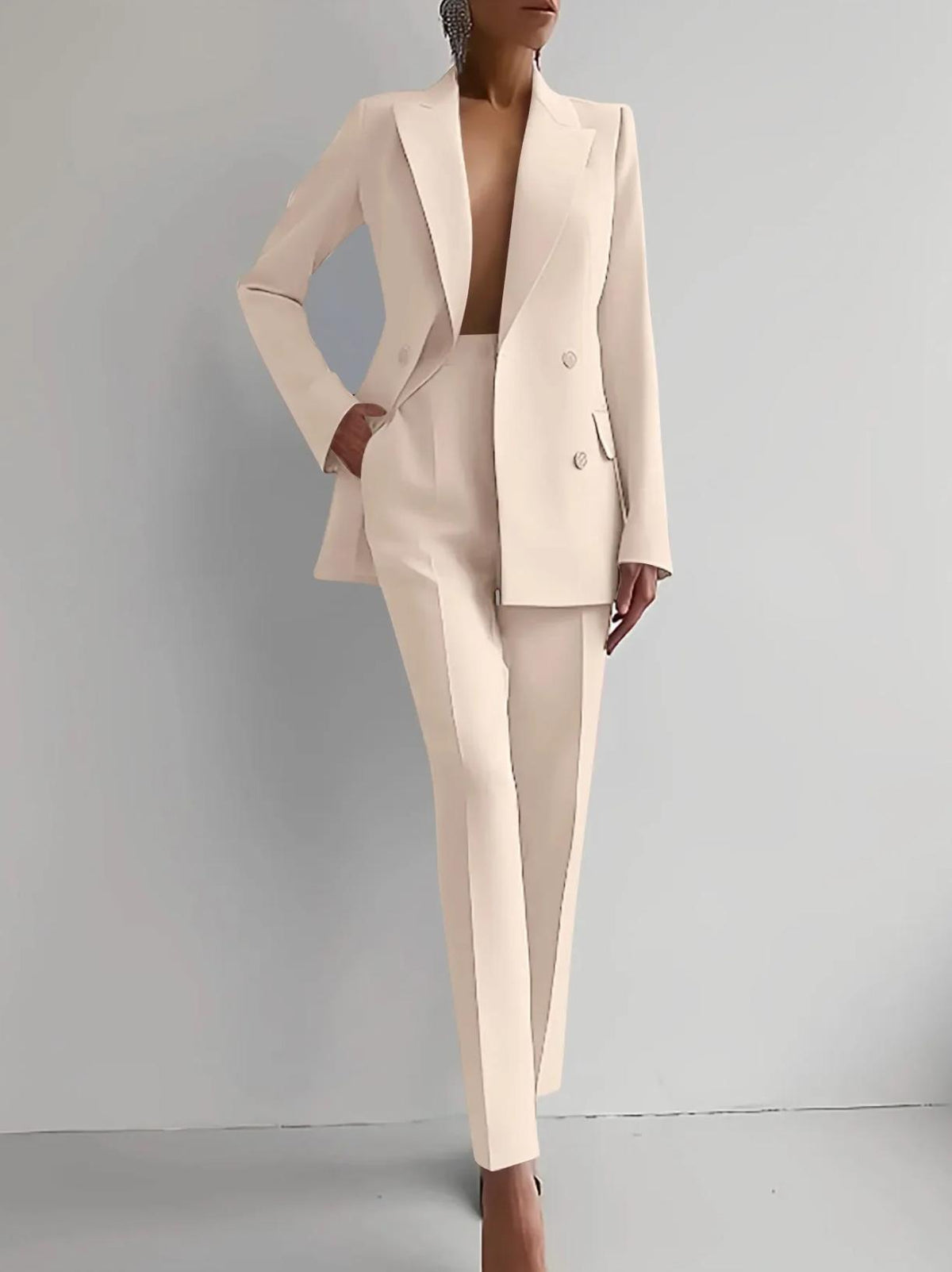 Woman wearing a cream-colored Italian satin double-breasted two-piece suit with tailored trousers.