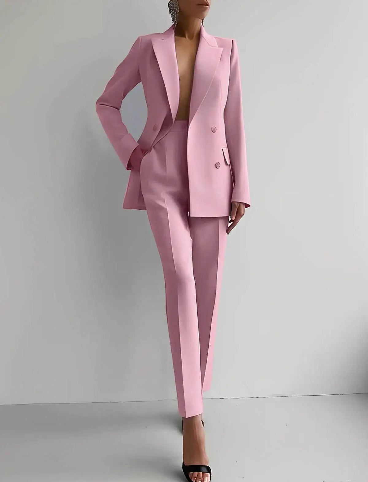 Woman wearing a tailored, double-breasted pink satin two-piece suit with slim-fit ankle-length trousers.
