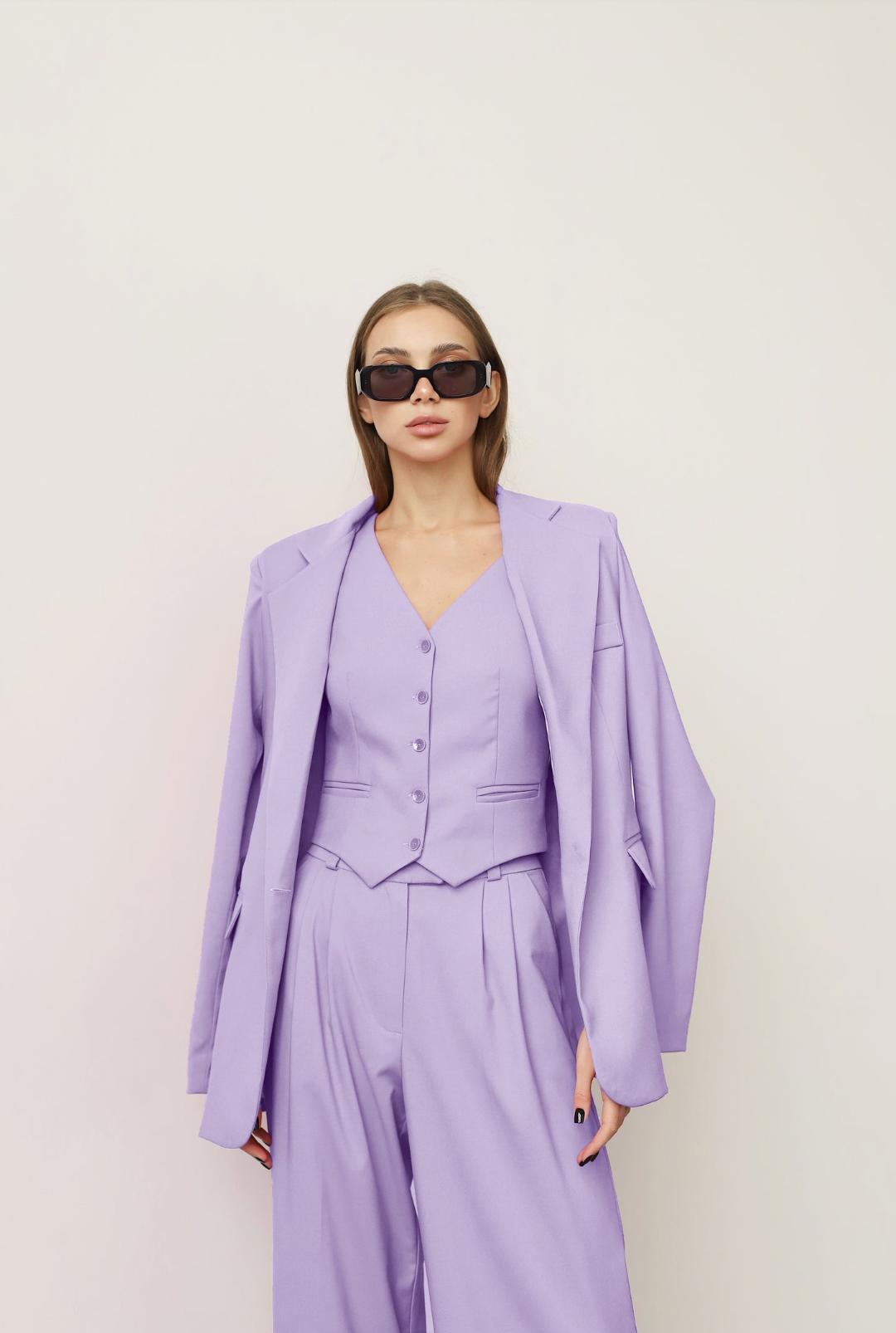 Woman wearing a lavender three-piece linen suit with a loose blazer, buttoned vest, and wide-leg pants with sunglasses.