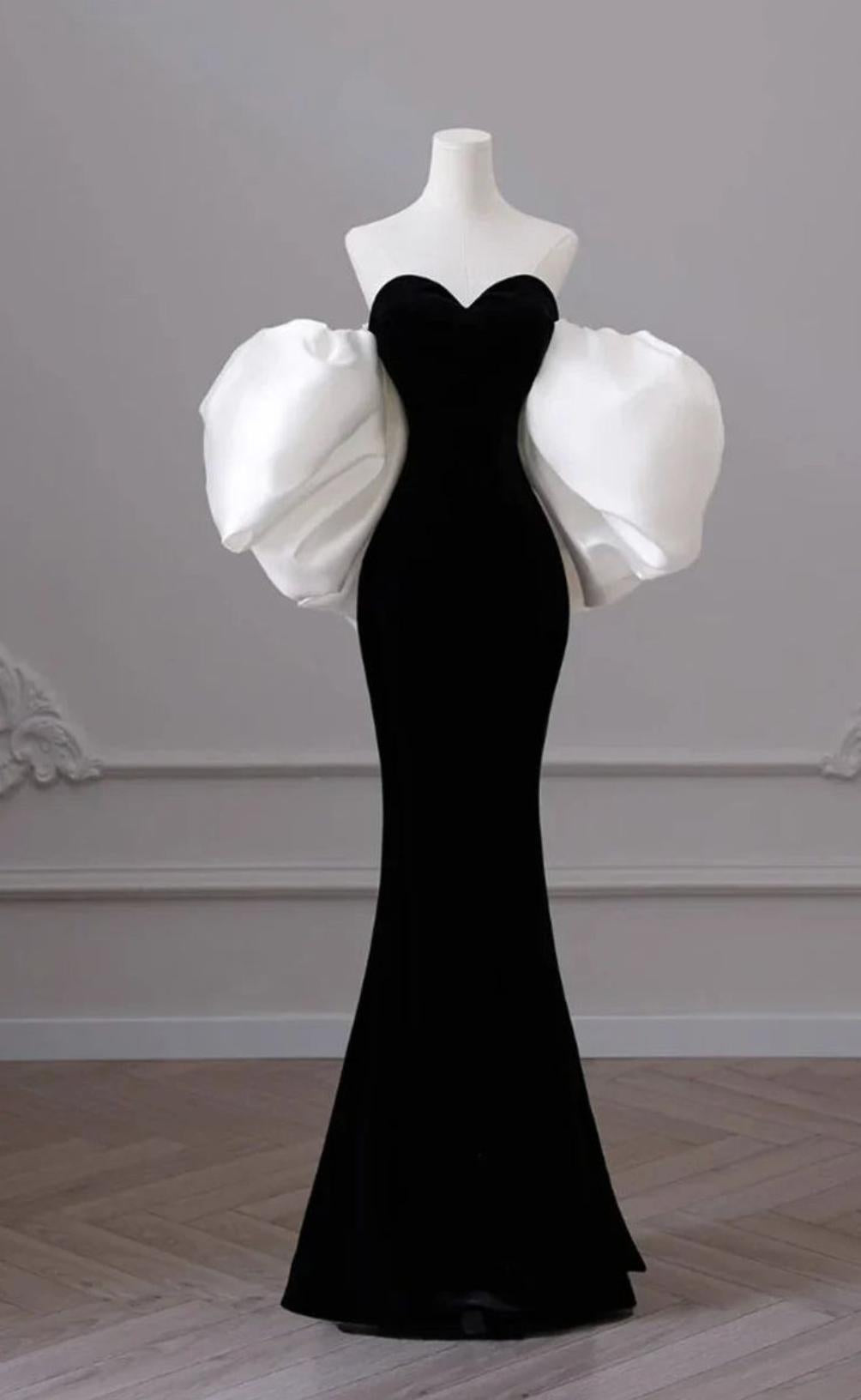Black velvet mermaid gown with a sweetheart neckline and voluminous white puff sleeves on a mannequin.